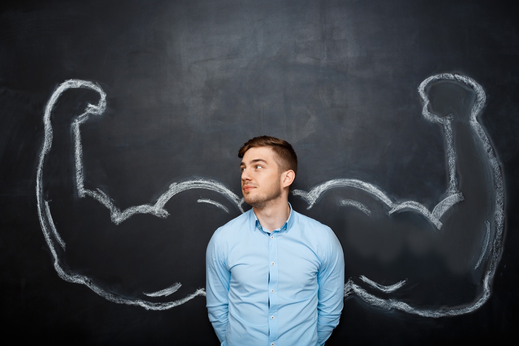 Picture of  funny suited business  man with  fake muscle arms over blackboard. hand whrite. look right
