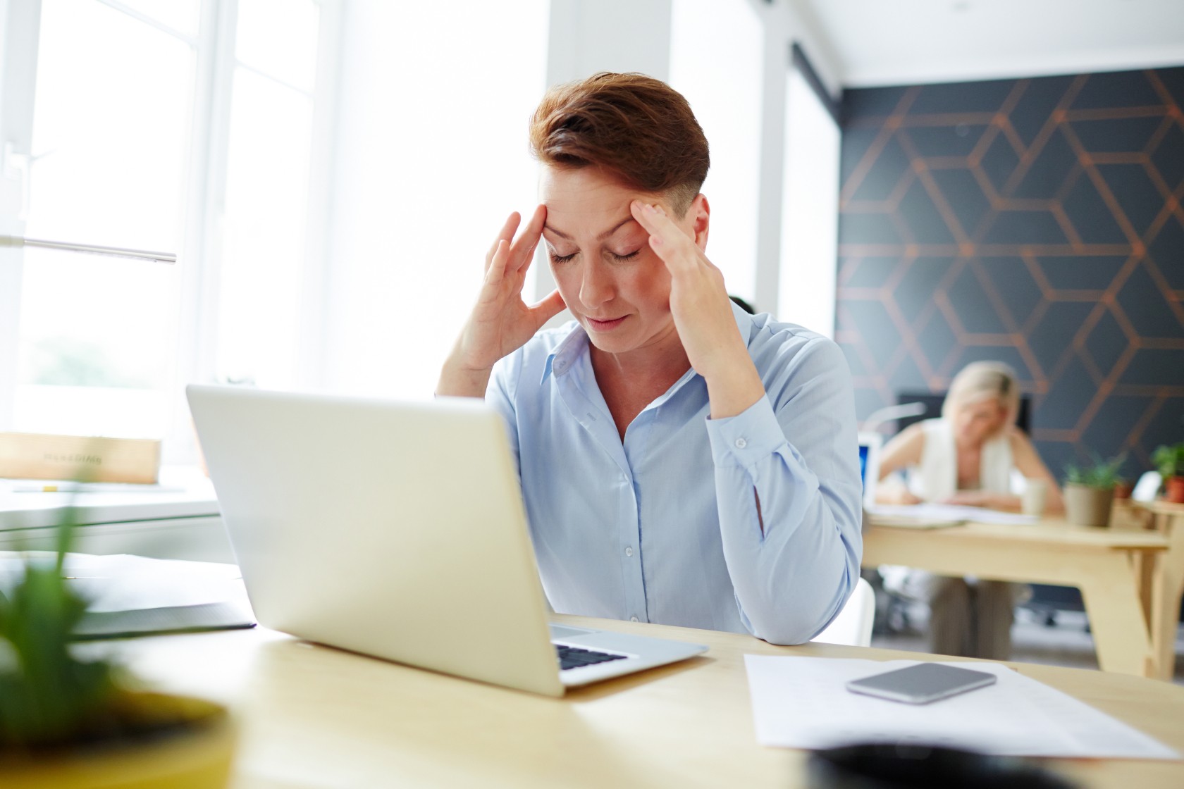 Tired or pensive woman sitting in front of laptop and preparing for report
